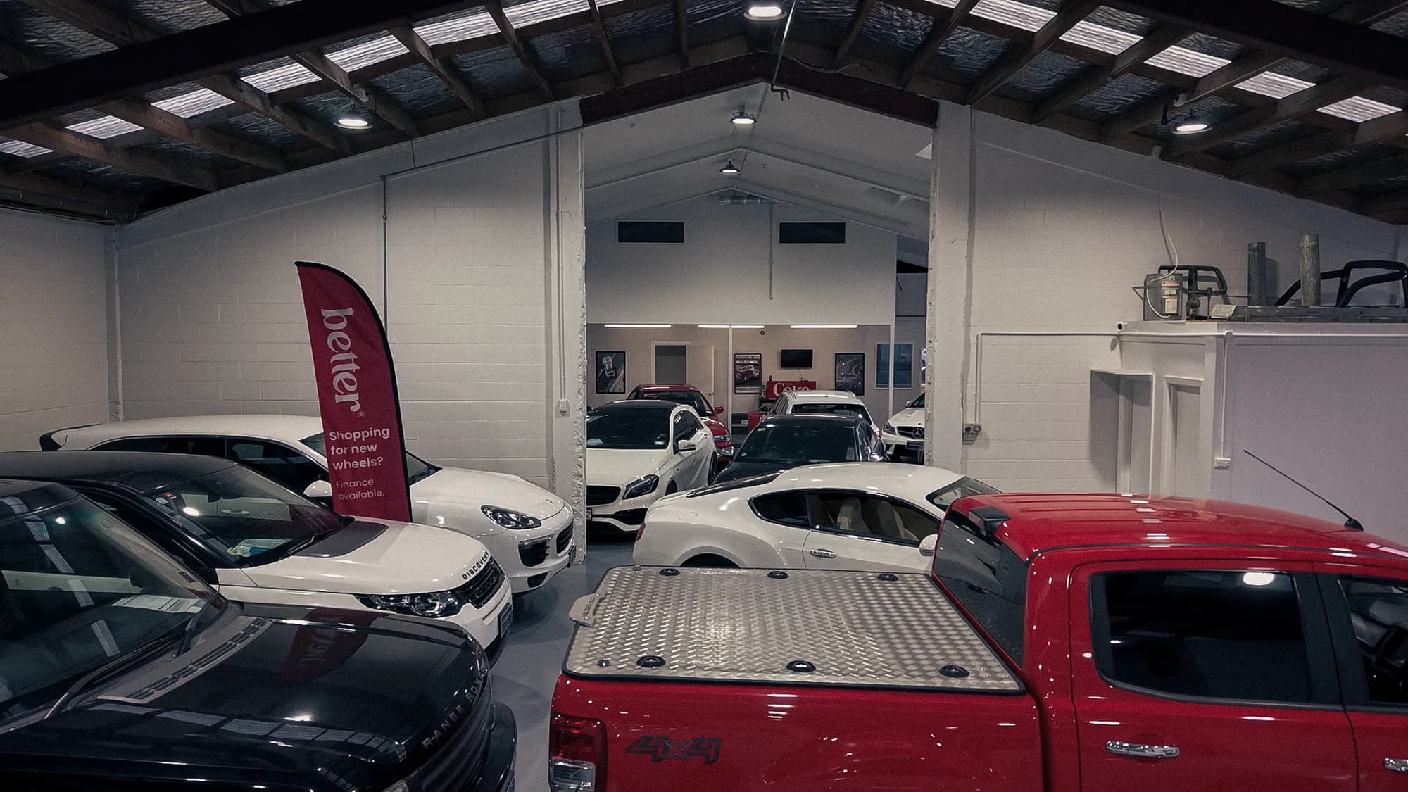 Indoor showroom floor with Range Rover, Porsche and pickup at Premium Wholesale Cars